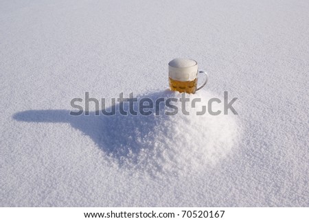 full mug of bright beer on piled hill snow