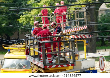 WARSAW, POLAND - AUGUST 31: Tram power grid maintenance works on August 31, 2014 in Warsaw, Poland. Workers in crane basket repair tramway electrification system on 11 Listopada street in Warsaw.
