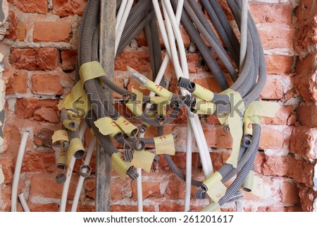 Close up of tangled electrical conduits on the brick wall.
