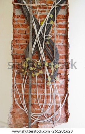Tangled electrical conduits on the brick wall.
