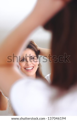 Happy woman looks at herself in the mirror