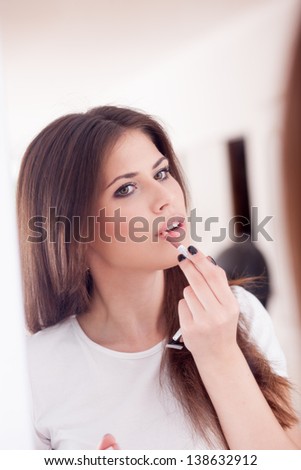 Portrait of a sexy girl putting make-up, looks in the mirror