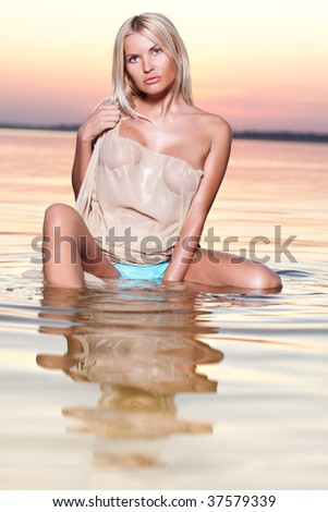 Woman sits in water, holds silk a right arm.