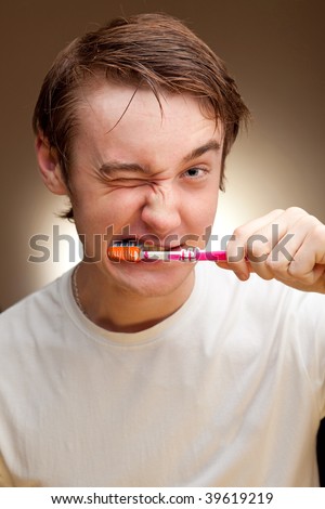 A funny young man cleans teeth.