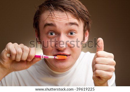 A funny young man cleans teeth.