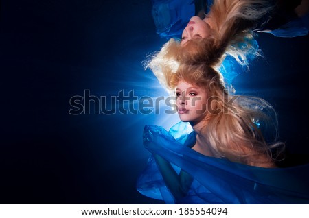 underwater photo pretty young girl  with blond long hair wearing blue fabric