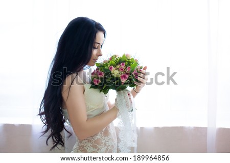 beautiful young bride in a white dress with a wedding bouquet of pink roses. Last preparations for the wedding. Bride waits for her groom. Morning, the bride.