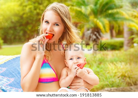 Beautiful mother and child in the open air. Nature. Beauty mother and her baby eat the fruit together. Outdoor portrait of a happy family. The joy. The baby and mother in the tropics.