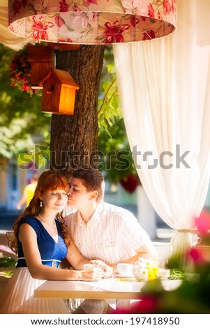 Outdoor portrait of young sensual couple in summer cafe. Love and kiss.