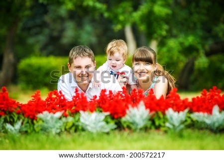 Happy family, mom, dad and little son having fun in the park. Summer vacations concept.