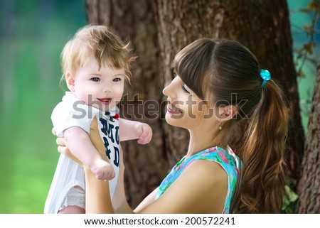 Happy family, mom and little son having fun in the park on the lake shore background. Summer vacations concept.