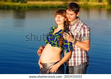 Happy and young pregnant couple having fun on the beach. Summer vacation. New life concept. Future mother and father.