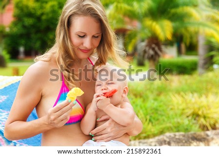 Beautiful mother and child in the open air. Nature. Beauty mother and her baby eat the fruit together. Outdoor portrait of a happy family. The joy. The baby and mother in the tropics.