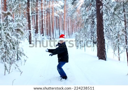 Two teenagers in Christmas hats Santa Claus having fun in the snow-covered forest playing in the snow.