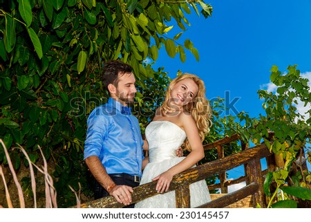 Happy bride in the wedding dress and groom smiling tropical plants in the background