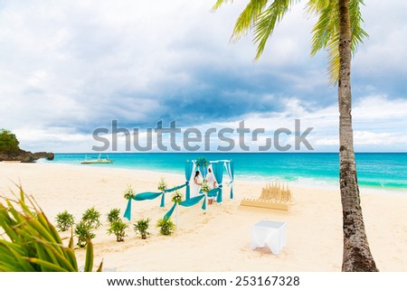 Wedding ceremony on a tropical beach in blue. Wedding arch decorated with flowers on tropical sand beach under the palm tree.