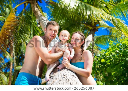Happy family, mom, dad and little child having fun on a tropical beach. Summer vacation concept. Outdoor portrait of a happy family.