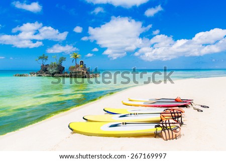 SUP surfing boards lie on a sandy tropical beach. Sea and island in the background. Summer vacation concept .