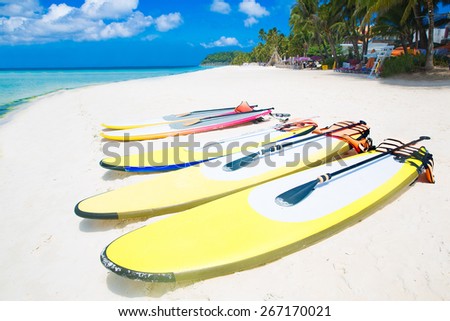 SUP surfing boards lie on a sandy tropical beach. Sea and island in the background. Summer vacation concept .