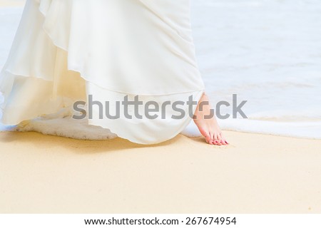 beautiful young bride in a white wedding dress walking on a tropical sandy beach. feet close-up.
