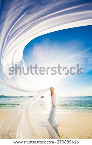 beautiful fiancee in white wedding dress and big long white train, stand on shore sea at sunset