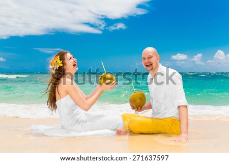 Happy bride and groom drink coconut water and having fun on a tropical beach. Wedding and honeymoon on the tropical island.