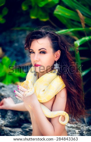 portrait of the beatiful girl with dangerous snake in the tropical jungle