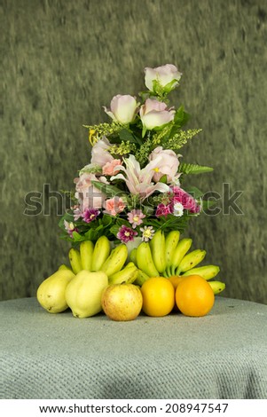 still life with a flower and fruits on table cloth.