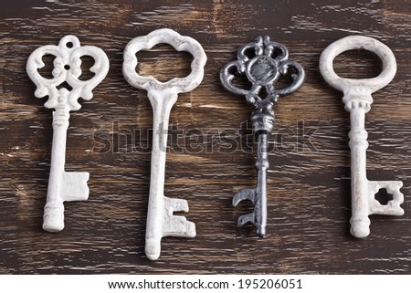 Set of four antique keys, one being different, on a wooden background