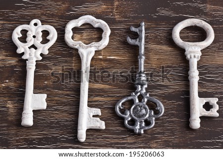 Set of four antique keys, one being different and upside down, on a wooden background