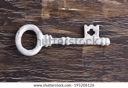 Single white antique key on wooden background