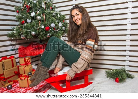 Beautiful and happy girl with gifts near a Christmas tree wishes everyone a Merry Christmas and Happy New year near a Christmas tree on artificial snow