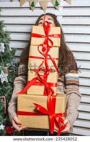 Beautiful and happy girl with gifts near a Christmas tree wishes everyone a Merry Christmas and Happy New year with presents