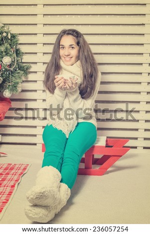 Beautiful and happy girl with gifts near a Christmas tree wishes everyone a Merry Christmas and Happy New year