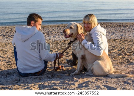Lovers walk along the seashore with dog, happy couple on the beach