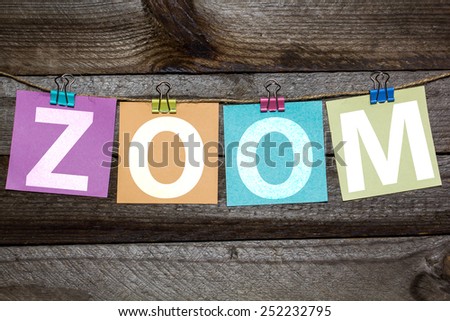 Message Zoom written on a paper hanging on the clothesline on wooden background