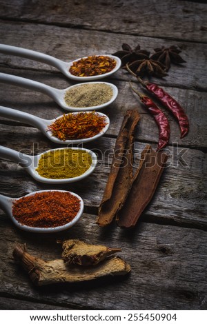 Powder spices on spoons in vintage wooden table background