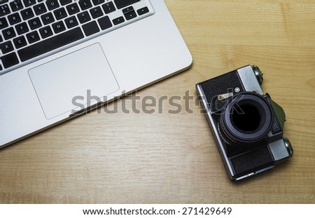 Laptop and camera on a wooden background