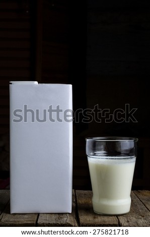 A glass of milk and a packet on vintage wooden table
