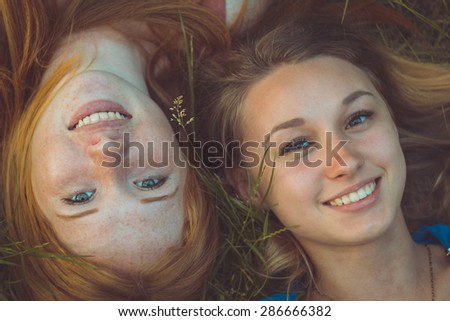 Red-haired girl and blond. Friends in summer park