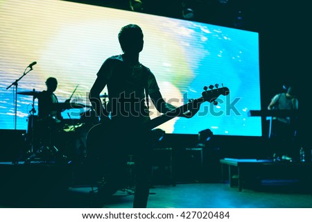 Blurred background light on rock concert with silhouette of musicians