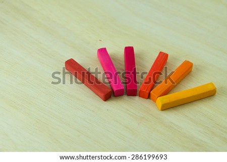 A group of chalk in warm tone colored. put down on plank,close-up view.