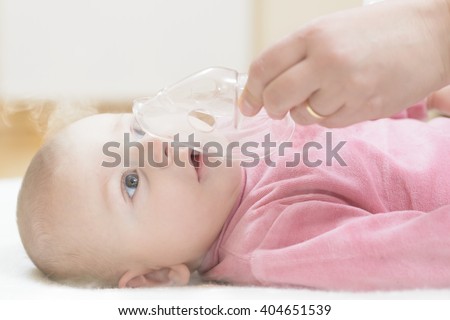 Baby taking respiratory therapy. Hand holding the mask of a nebuliser.