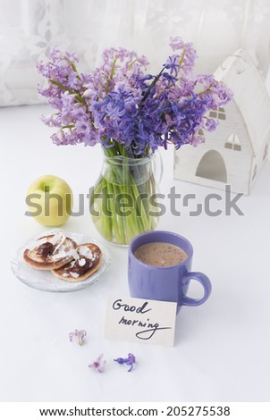Hyacinthus flowers in a transparent jar with god morning note, house candle holder and breakfast
