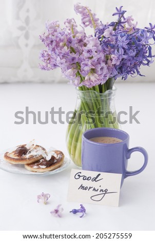 Hyacinthus flowers in a transparent jar with good morning note, house candle holder and breakfast