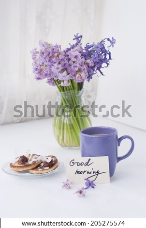 Hyacinthus flowers in a transparent jar with good morning note, house candle holder and breakfast