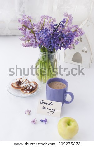 Hyacinth flowers in a transparent jar with god morning note, house candle holder and breakfast