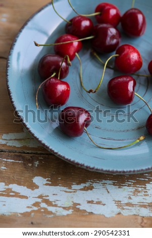 Blue ceramic shabby plate full with dark red juicy cherries