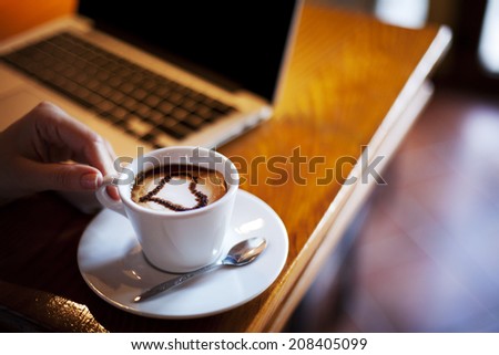 Woman holding cup of coffee. Heart shape in the cup.
