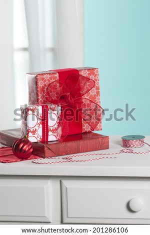 Presents and ribbon on dresser in front of a window inside a home. Shot with copy space.